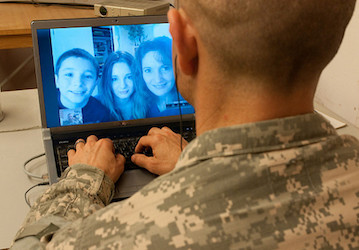 Soldier on deployment communicating with family via computer to facilitate emotional support for better resilience and milita
