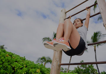Woman doing bent knee pull-ups on playground bars improves physical fitness and performance with core training  
