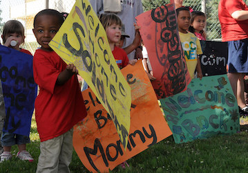 Children holding  welcome home  signs for military family members display resiliency and healthy coping during deployment   U