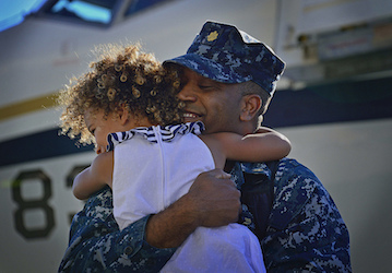 Sailor in uniform practices military wellness and healthy relationship communication by hugging his daughter   U S  Navy phot