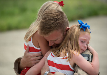 Service Member hugging his two daughters relies on HPRC family resources for improved communication during deployment   U S  