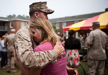 Military member hugging goodbye before deployment hopes to maintain mental health by practicing holistic relationship communi