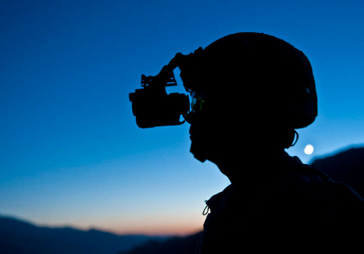 Soldier keeps watch through his night vision goggles as the sun sets from a hilltop  Photo by U S  Army Staff Sgt  Mark Burre