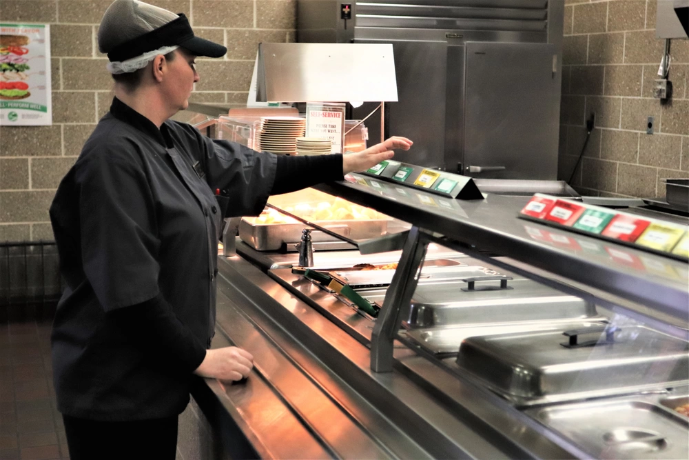 DFAC worker sets up food cards on serving line