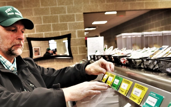 DFAC worker positions food cards on serving line