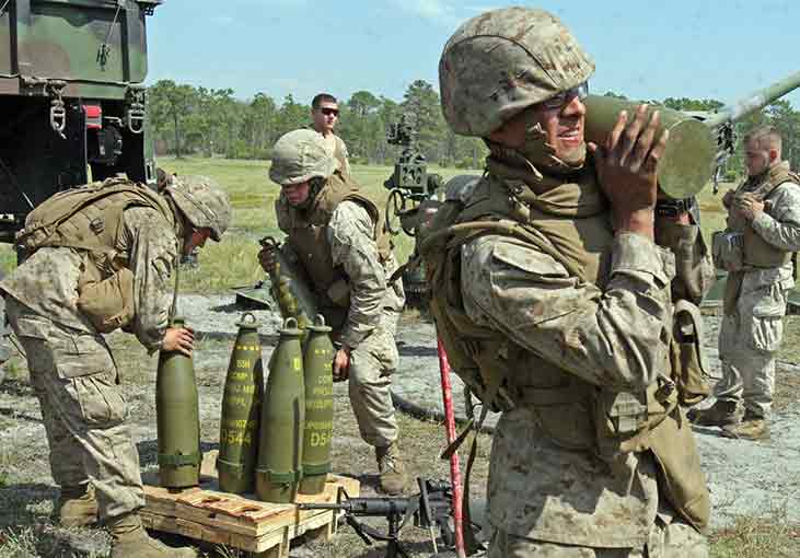 Marines with Battery A, 1st Battalion, 10th Marine Regiment, 2nd Marine Division, grit their teeth as they shoulder the 100 pound rounds