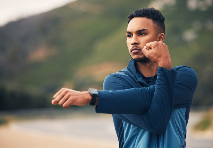 Runner man, stretching arms and mountain with thinking for fitness, health or wellness in street.