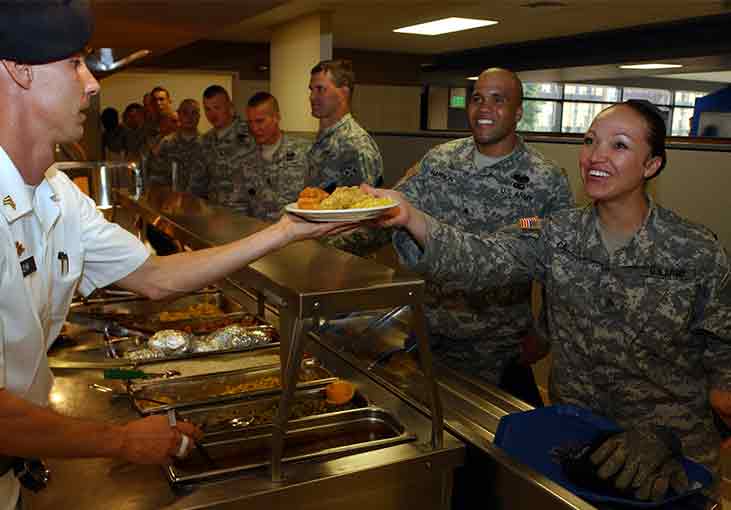 Sgt. Jessica Casados, 3rd Brigade Combat Team, 4th Infantry Division, receives her "surf and turf" meal from Sgt. Brett Lehr, a cook from 2nd Squadron, 9th Cavalry, during the grand opening meal at the Striker Café.