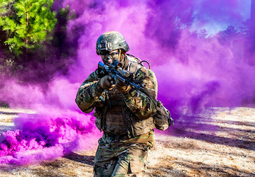 Soldier standing in front of a purple cloud takes part in military training event to optimize performance with Total Force Fi