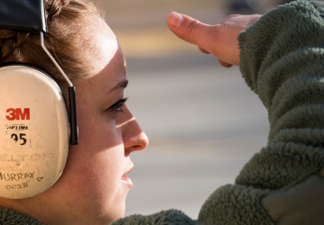 Female Airman looking into sun with hand covering eyes