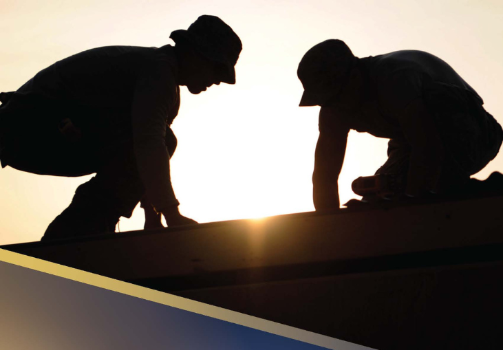 Silhouettes of two people working on ground sun in background