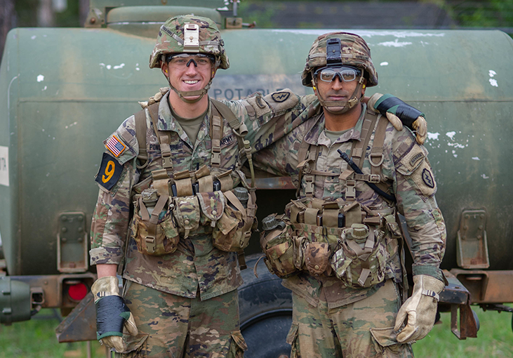 Two men in uniform smile arm in arm