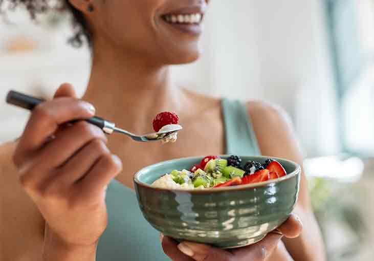 Woman with a bowl of oatmeal and fruit